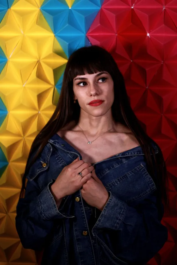 Portrait in front of a yellow, blue and red folded-paper wall